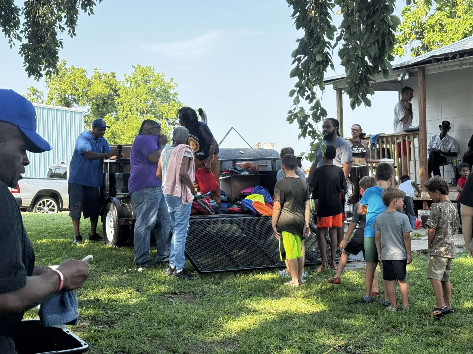 Children and volunteers gather around a trailer filled with colorful bookbags