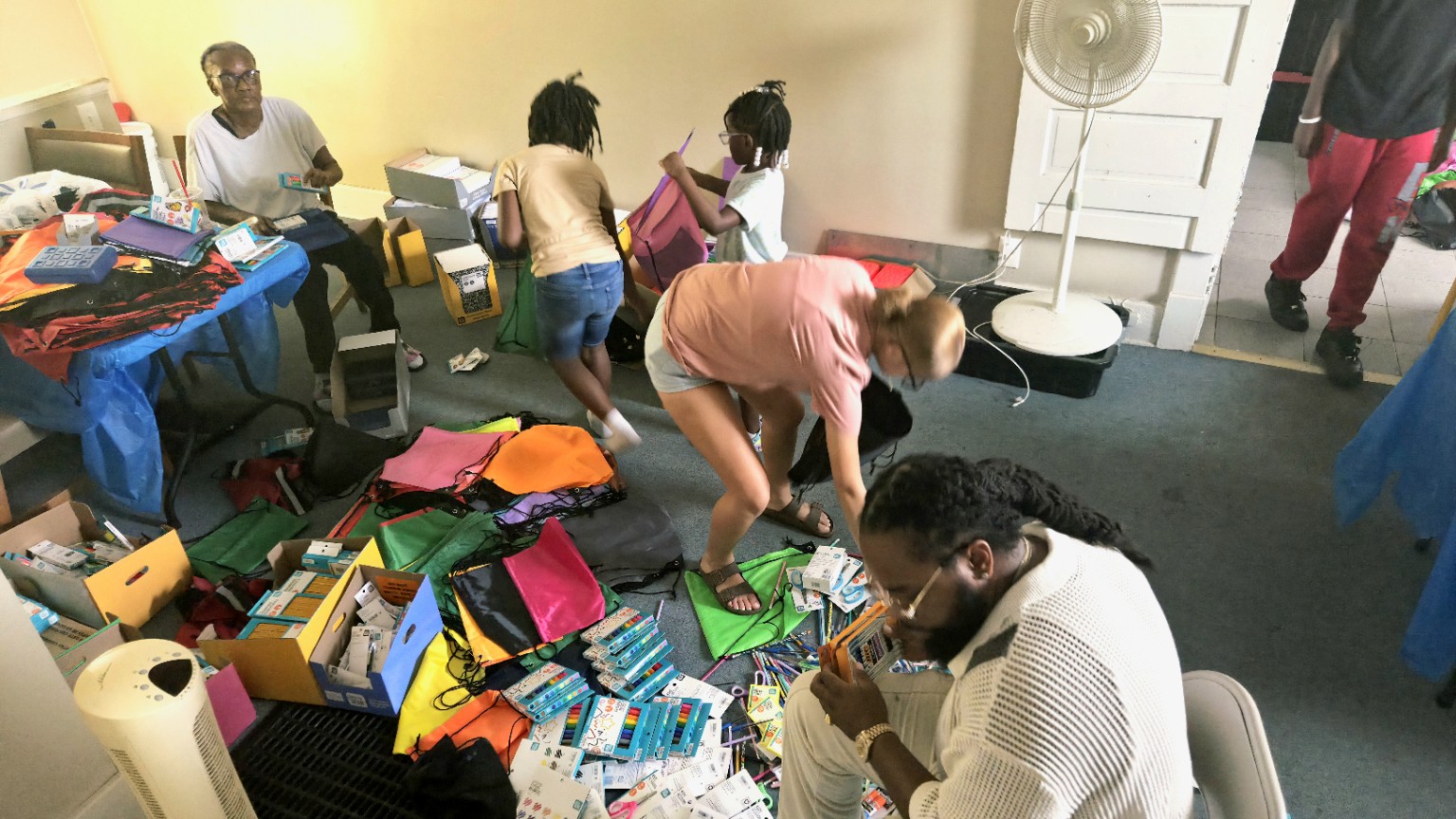 Families and volunteers prepare school supplies and colorful bookbags for the giveaway