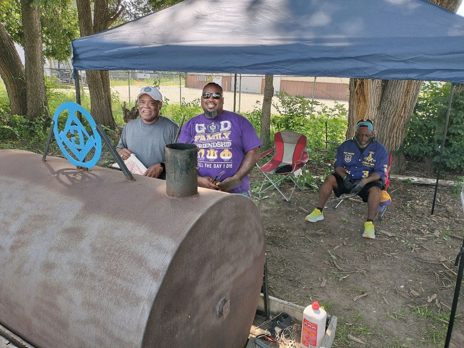 Brothers support the community meal beside the lodge smoker