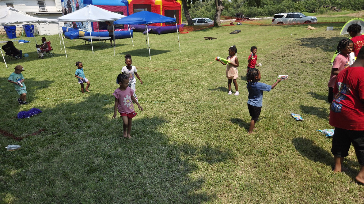 Children enjoy the water war with a colorful bounce house in the background