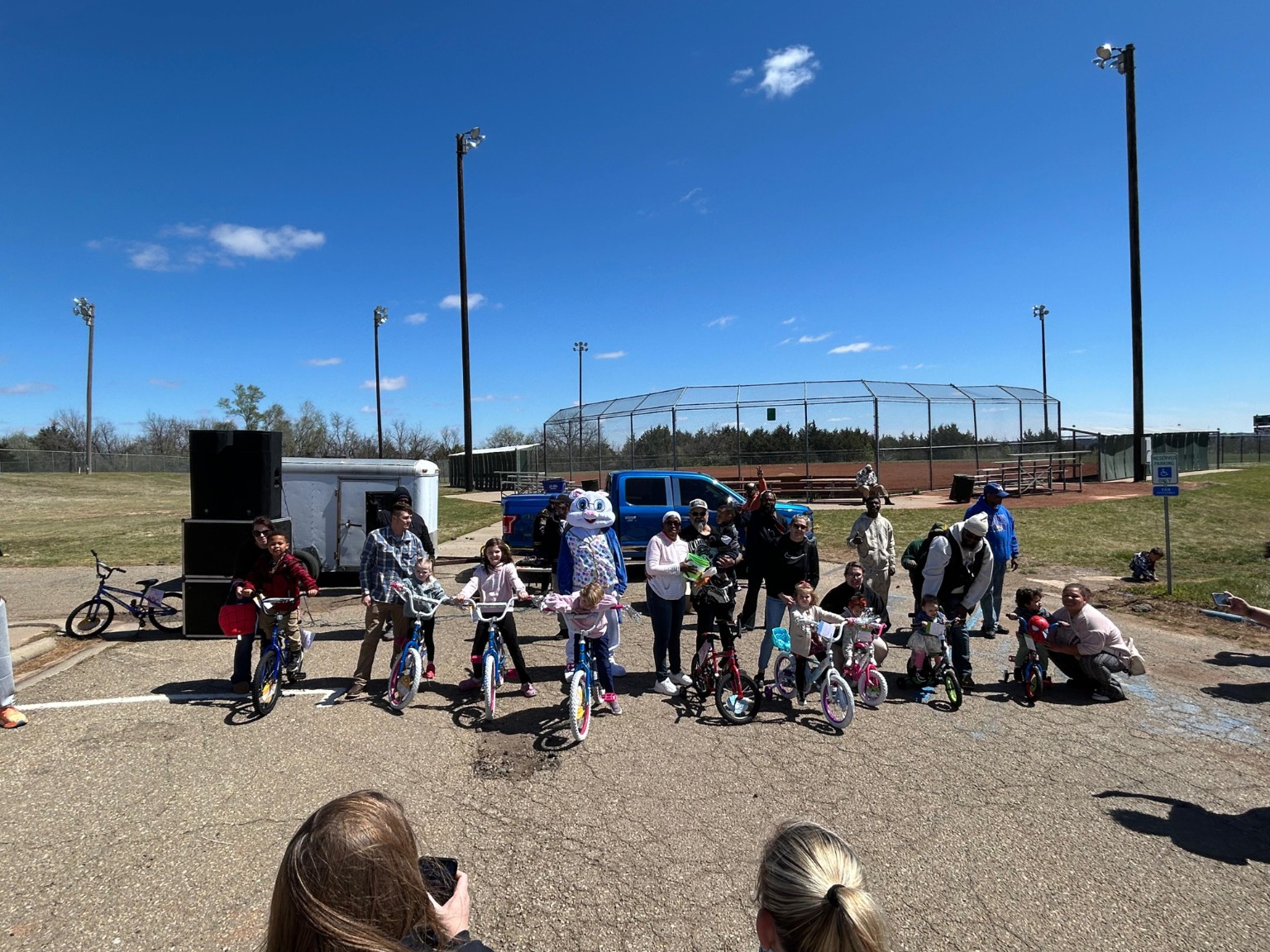 Children pose on giveaway bicycles with families, lodge brothers, and the Easter Bunny